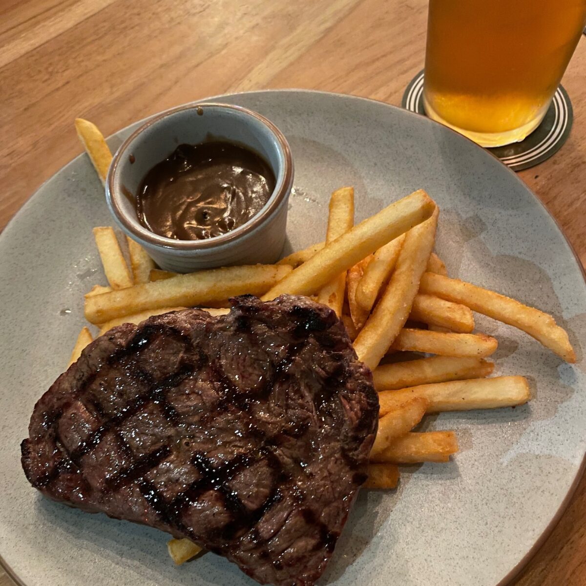 Large steak with char cross marks, chips and a bowl of sauce